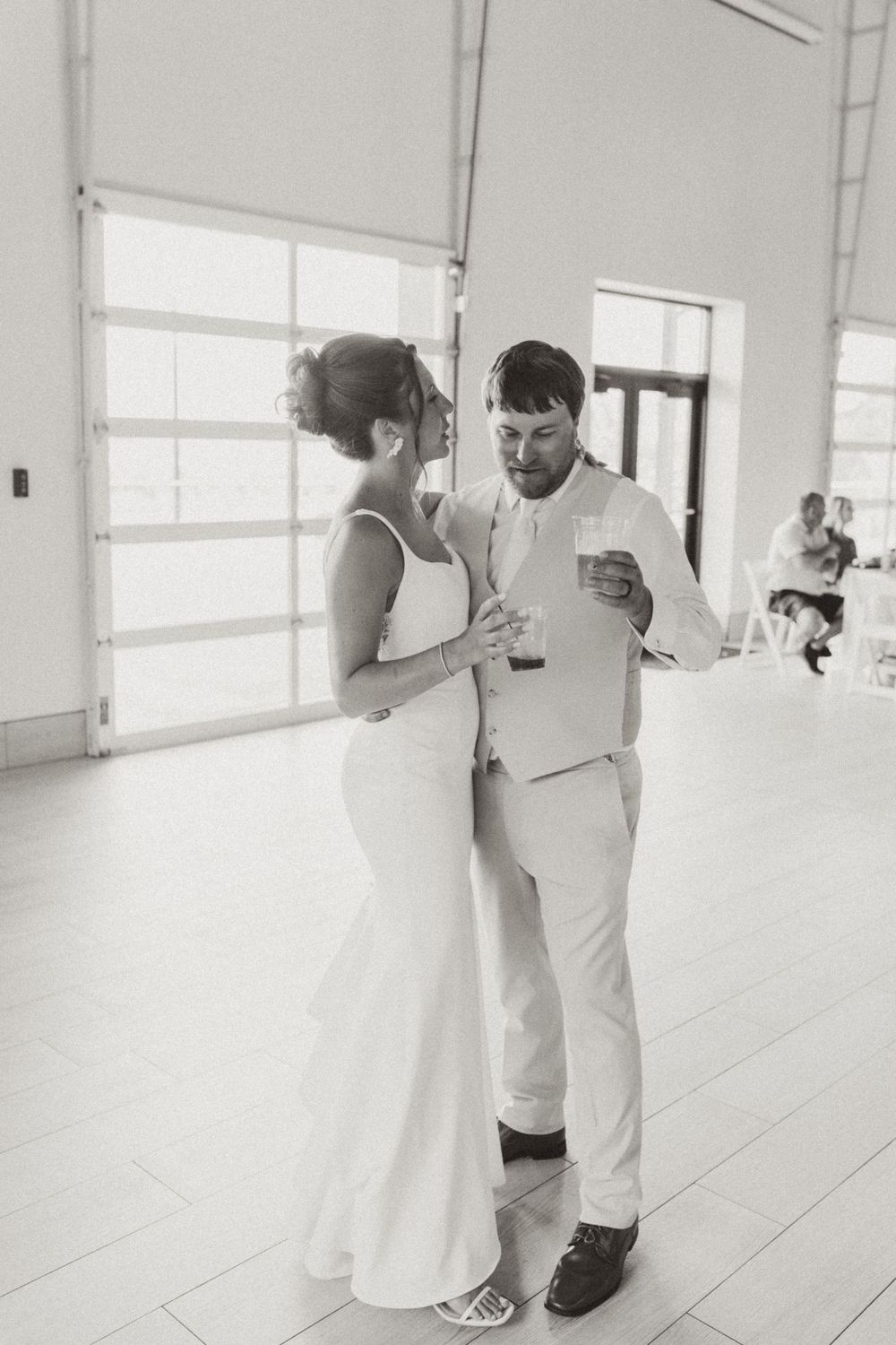 A couple shares an intimate dance moment in a bright indoor venue.