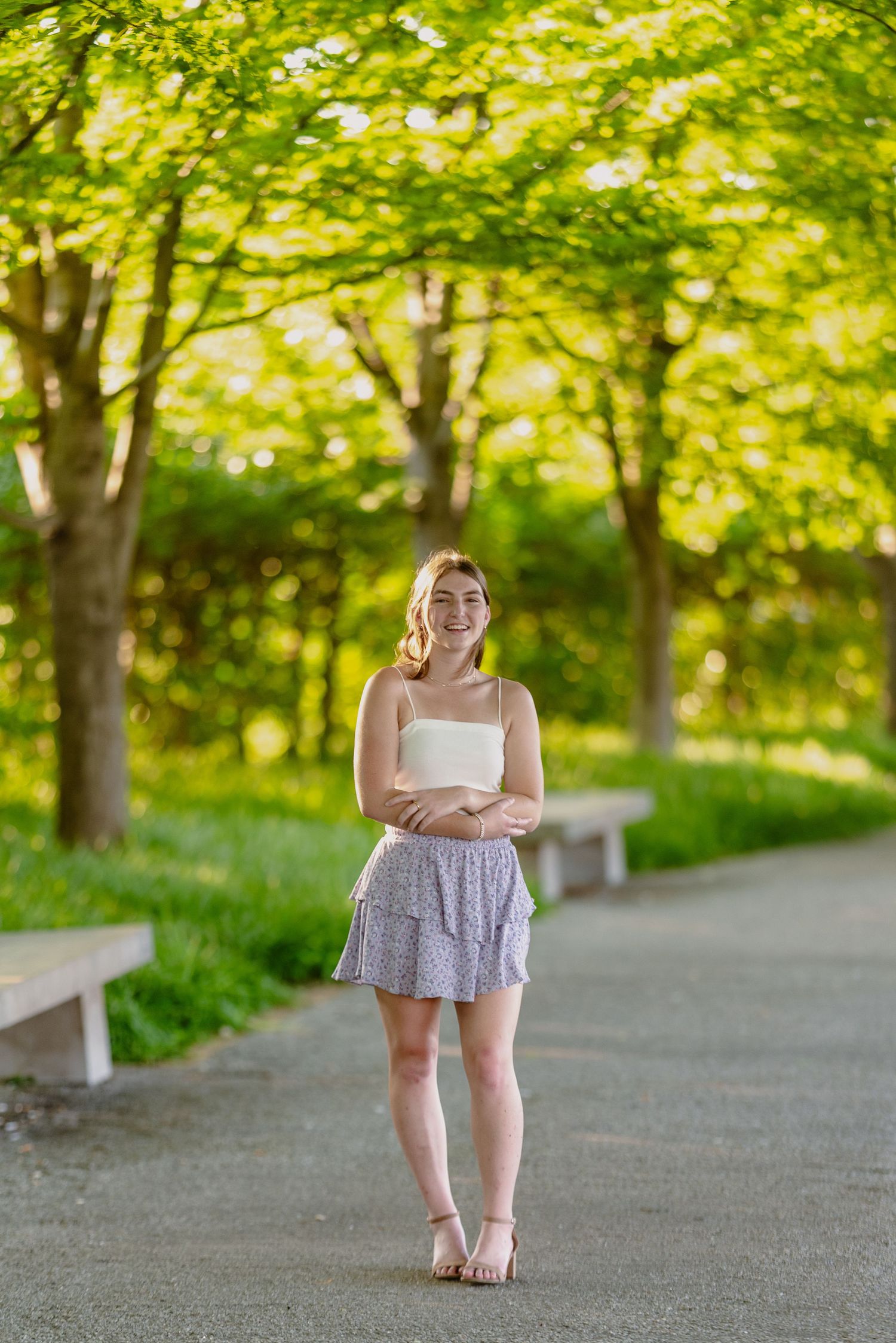 Young person in summer dress walking along a tree-lined path.