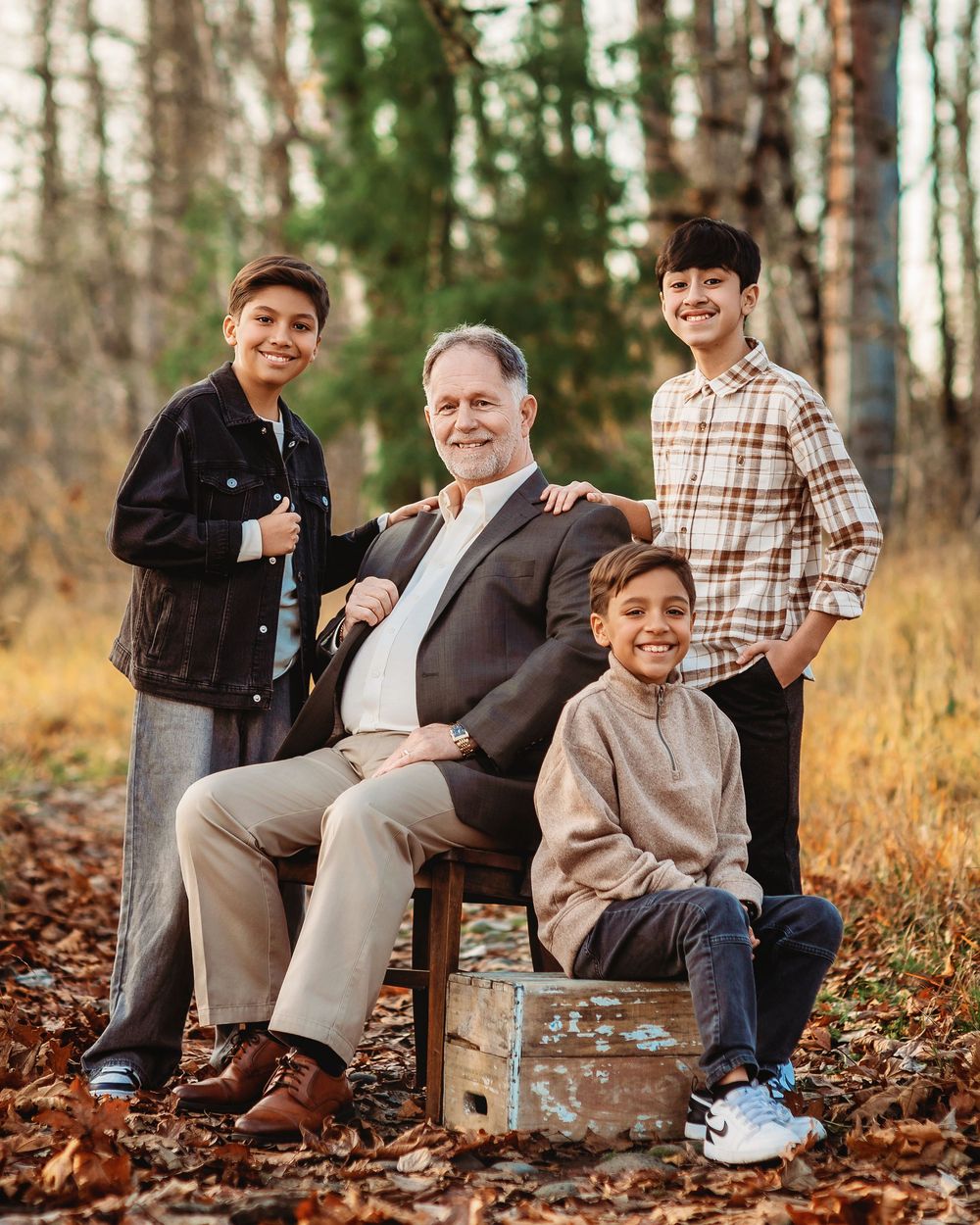 A series of four connected photos showing people sitting on fallen autumn leaves in a wooded outdoor setting.