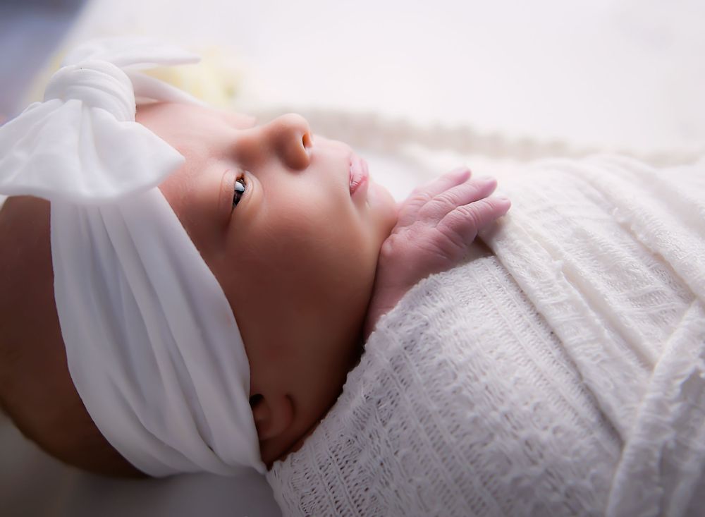 Newborn girl backlit studio portrait by Nicola in Woodside, soft glowing light capturing delicate timeless newborn details and warmth.