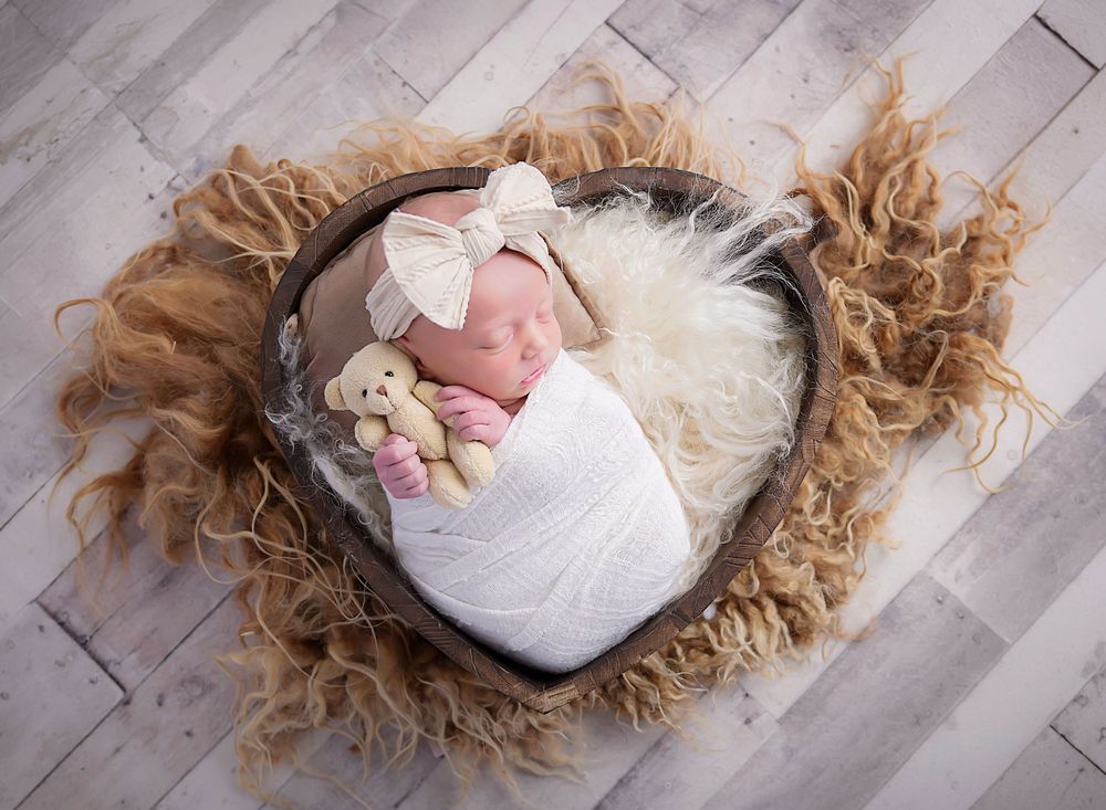 Newborn baby in heart shape prop on fluffy neutral layer, soft studio portrait by Nicola in Woodside capturing timeless delicate details.