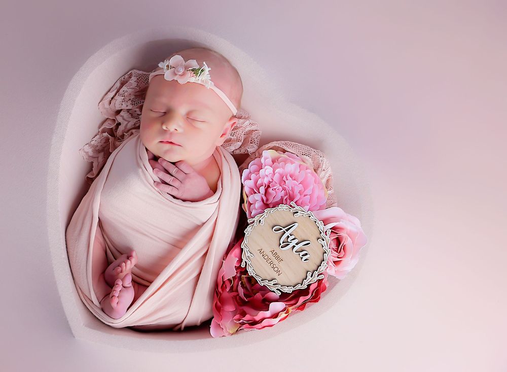 “Newborn photography by Nicola in Woodside, Glenrothes featuring a sleeping baby in a heart-shaped bowl with soft pink tones.