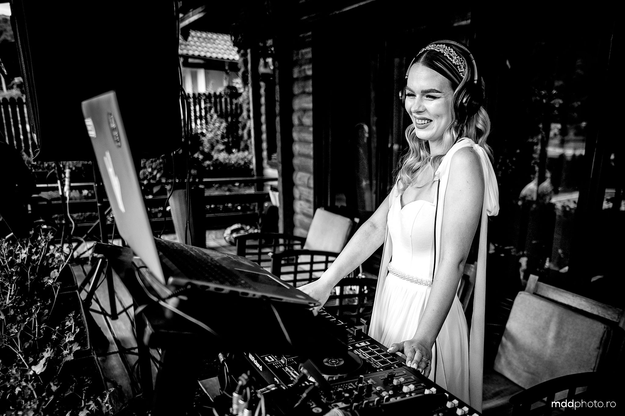Black and white photo of a pianist performing at a piano in a classic sleeveless white dress and headband.