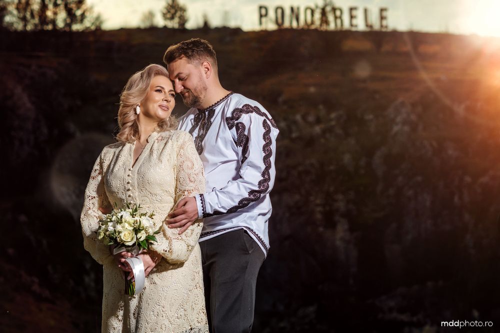 A romantic wedding couple shares an intimate moment at sunset in front of a rustic Bondville sign.
