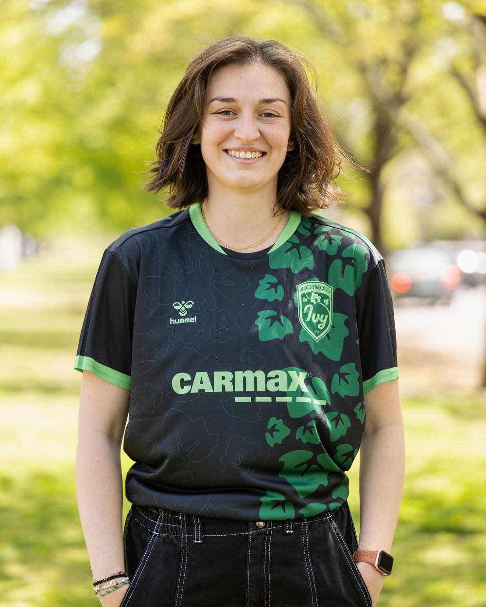 Person wearing a black and green CarMax jersey with shamrock designs.