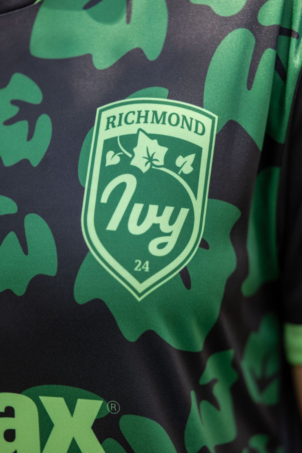 Close-up of Richmond soccer team jersey with green ivy pattern and shield logo.