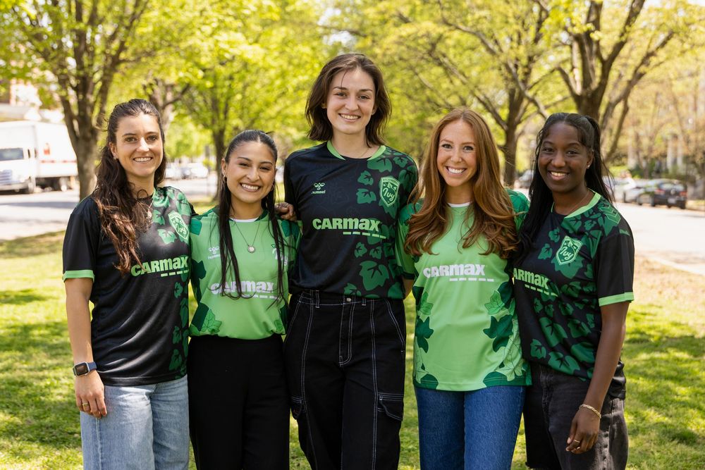 Group wearing matching green and black soccer team uniforms posing outdoors.