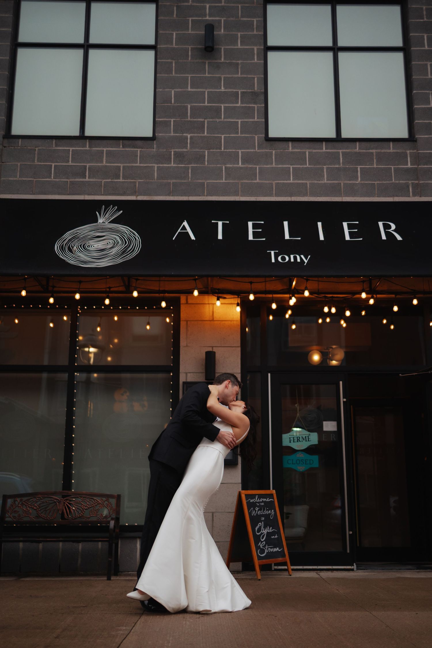 Wedding couple dancing outside a storefront with 'Atelier' signage.