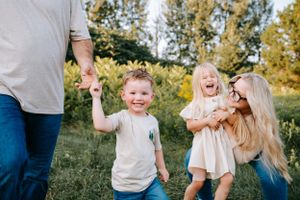 A candid family moment captured during playtime outdoors in golden evening light.