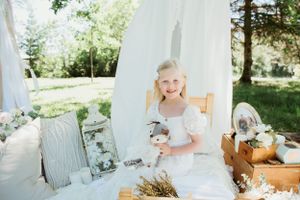 Garden tea party scene with white draping, wooden furniture and rustic decorative elements.