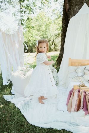 Whimsical garden party setup with white fabric draping and mauve ribbon details.