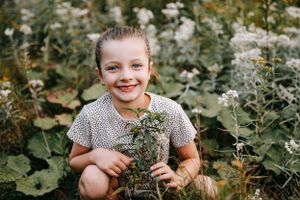 Child playing joyfully in a wildflower garden during golden hour.