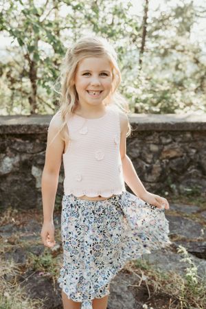 A sunny portrait showing a bright smile and floral patterned summer outfit.