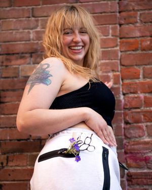 A series of maternity photos showing a woman in black against a brick wall with purple flowers.