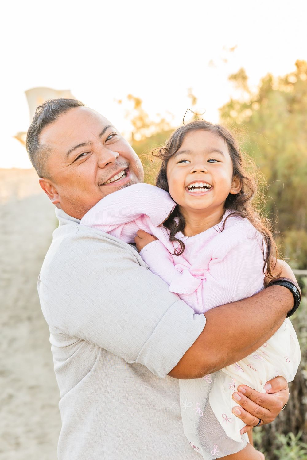 A joyful embrace between an adult and child at sunset in a natural outdoor setting.