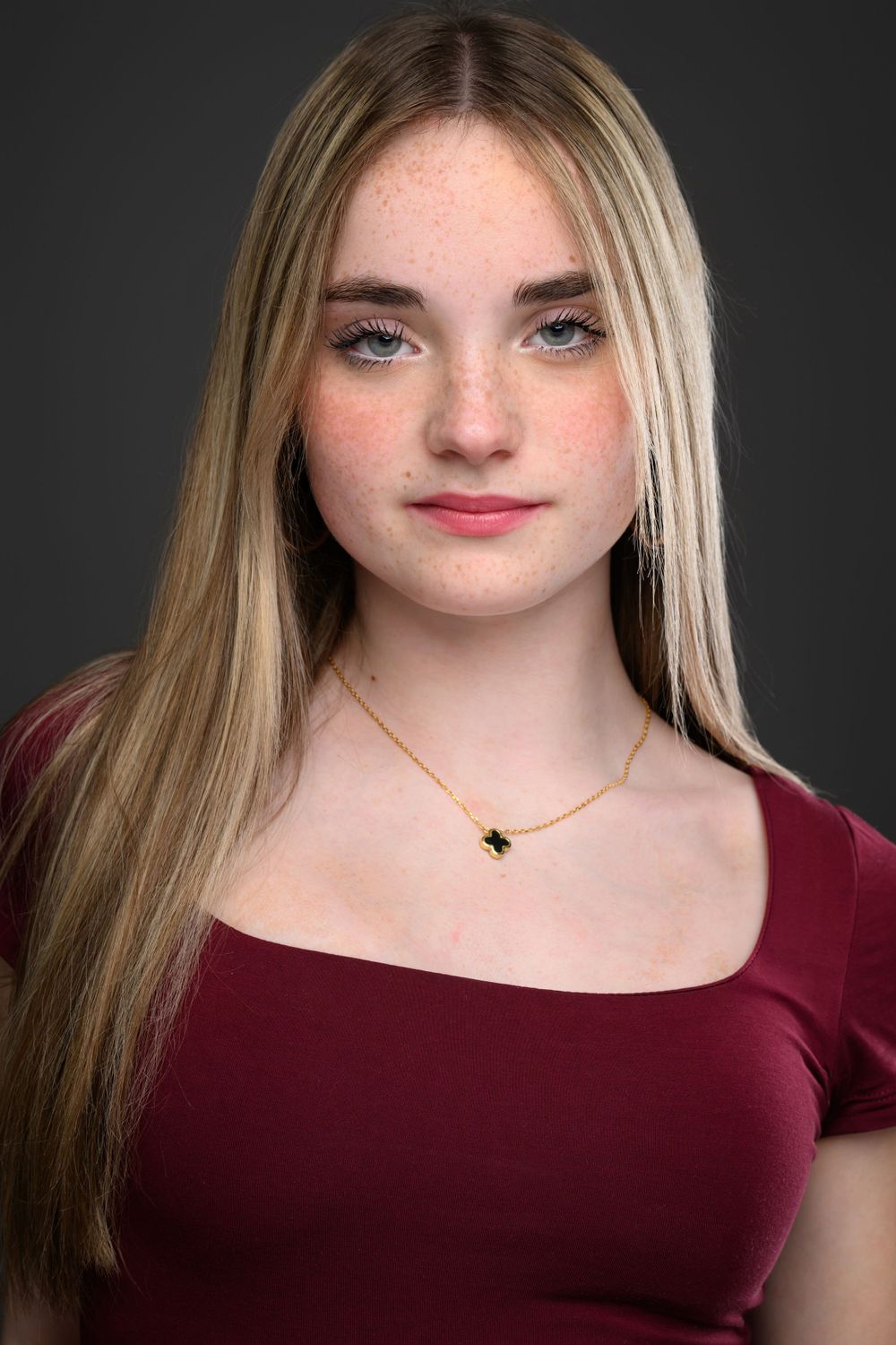 Professional headshot series in a burgundy top against dark backdrop.