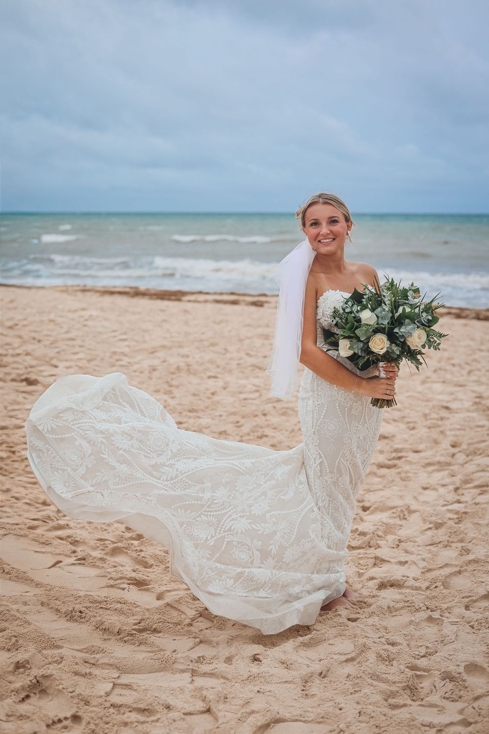 A beautiful beach wedding portrait with flowing lace dress and white floral bouquet. Wedding photography, travel photography.