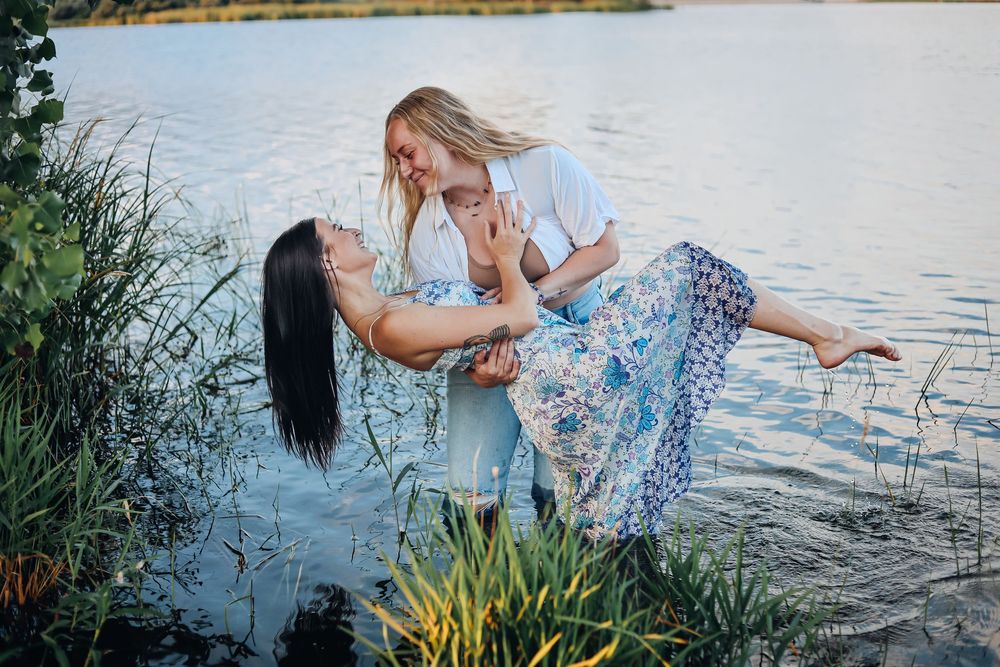 Romantic couple photoshoot by a lake with flowing blue floral dresses. Couples photography, LGBTQ+