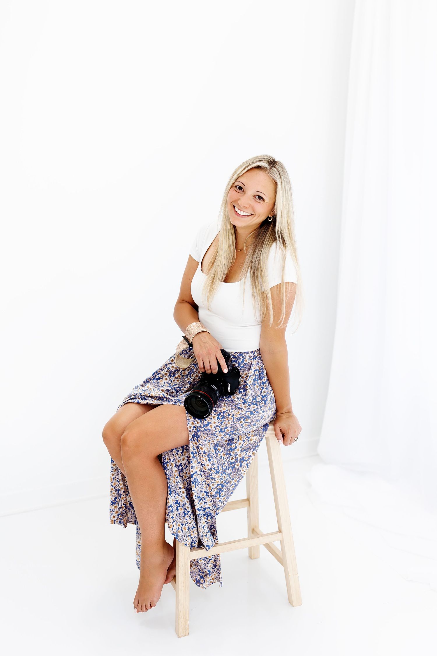 Professional portrait session against white backdrop featuring soft pink off-shoulder top styling.