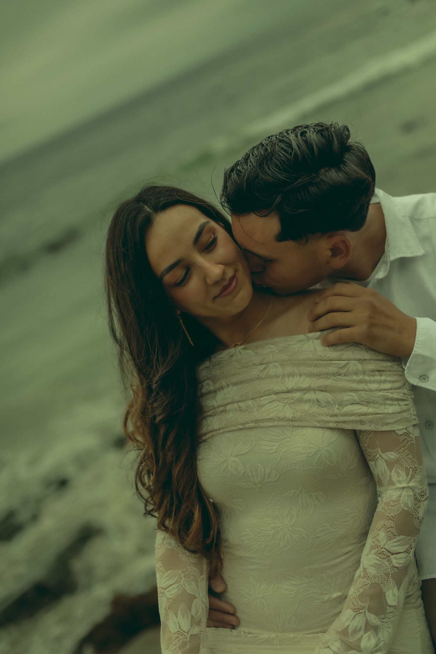 Romantic couple embraces on a beach on an overcast day creating an intimate atmospheric moment in Southern California.