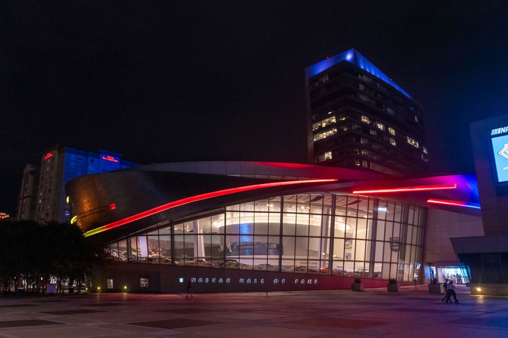 Modern architectural building illuminated with blue and red lights at night creating a dramatic urban cityscape.