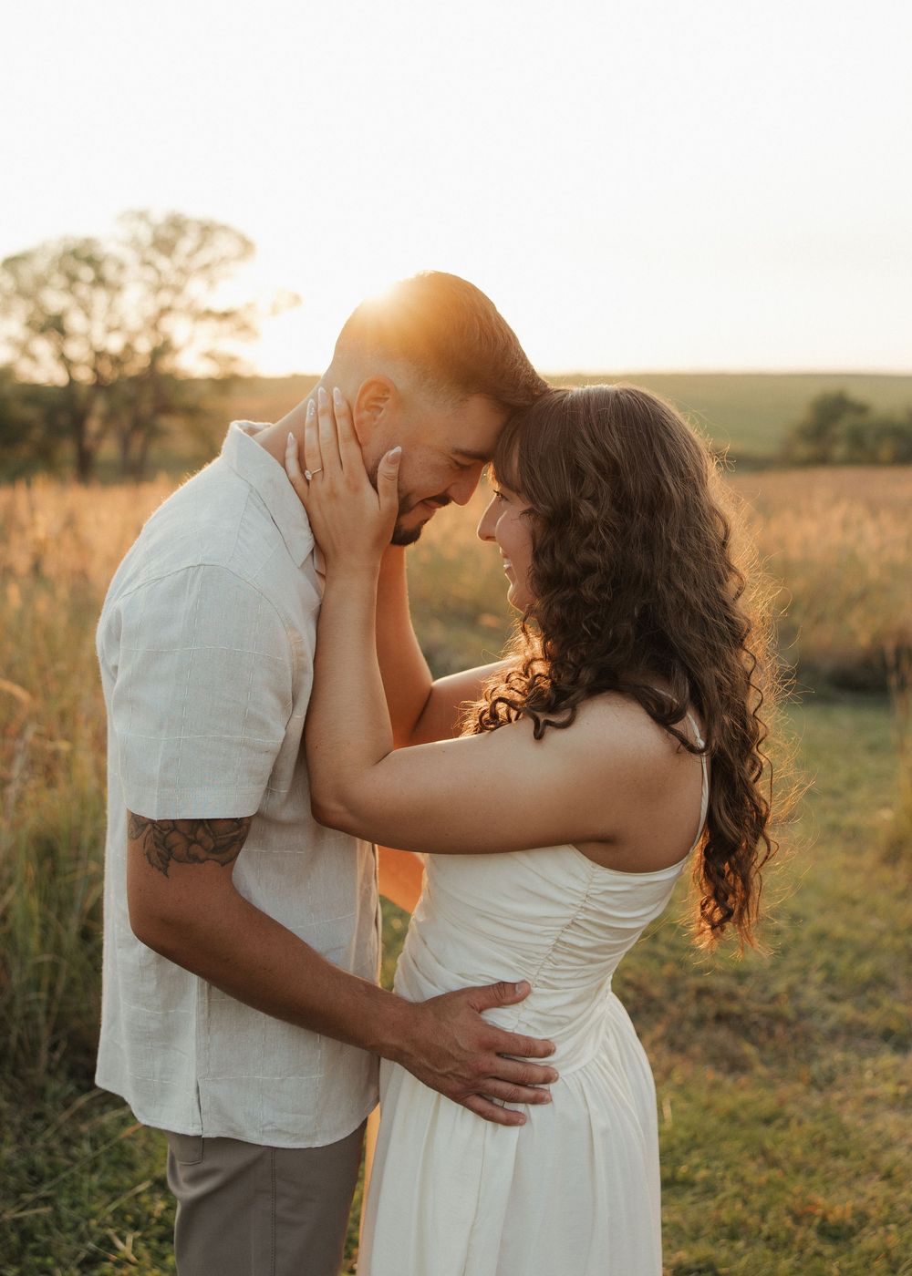 A romantic couple embraces in a golden field during sunset creating a dreamy silhouette against the warm light.