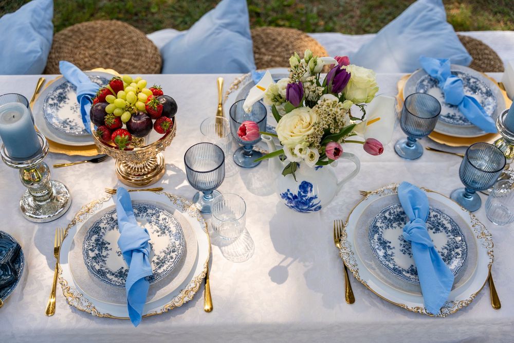 Romantic outdoor picnic setup with blue decor and refreshments arranged on a blanket  seaside