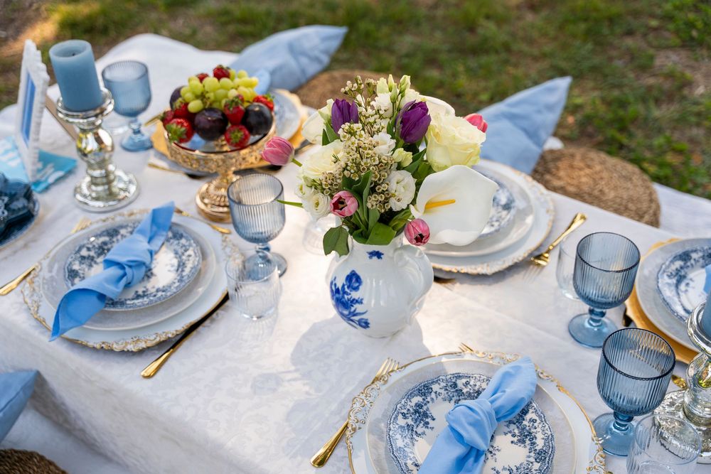 Romantic outdoor picnic setup with blue decor and refreshments arranged on a blanket  seaside