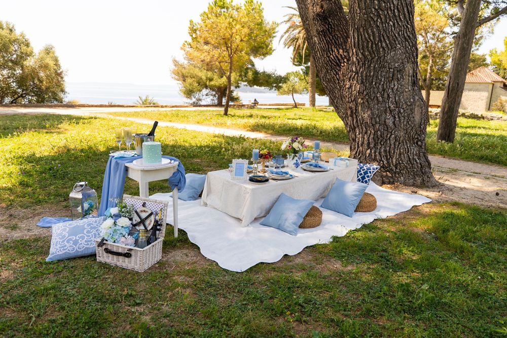 Romantic outdoor picnic setup with blue decor and refreshments arranged on a blanket  seaside