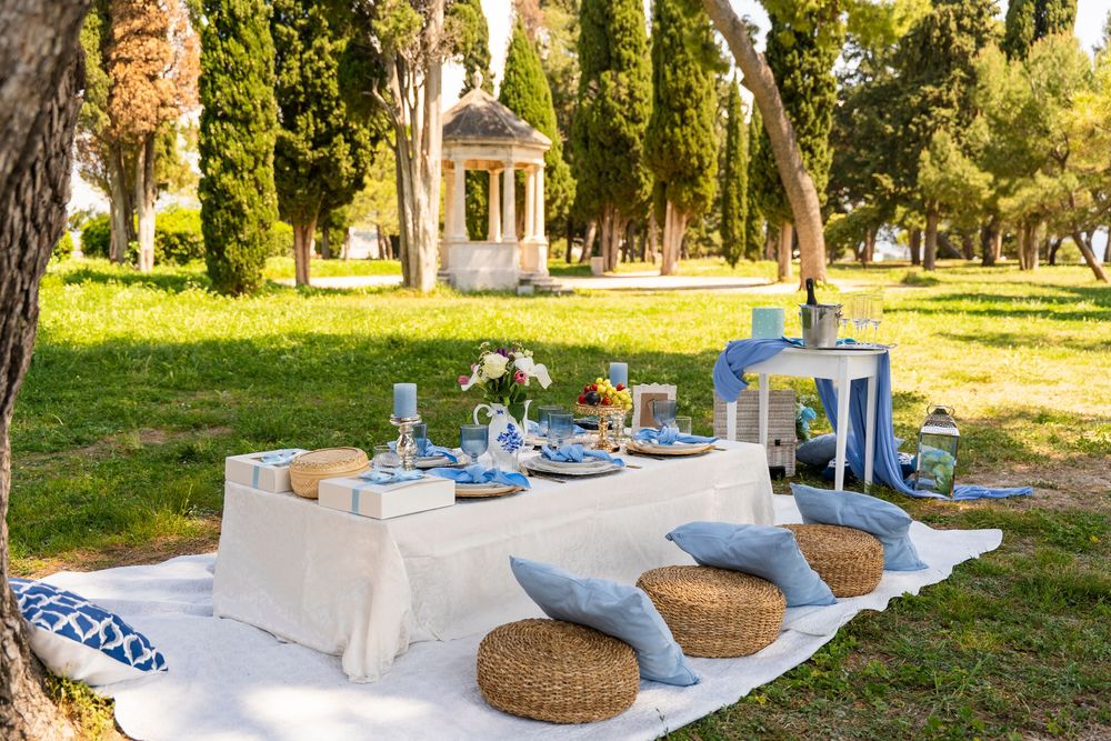 Romantic outdoor picnic setup with blue decor and refreshments arranged on a blanket  seaside