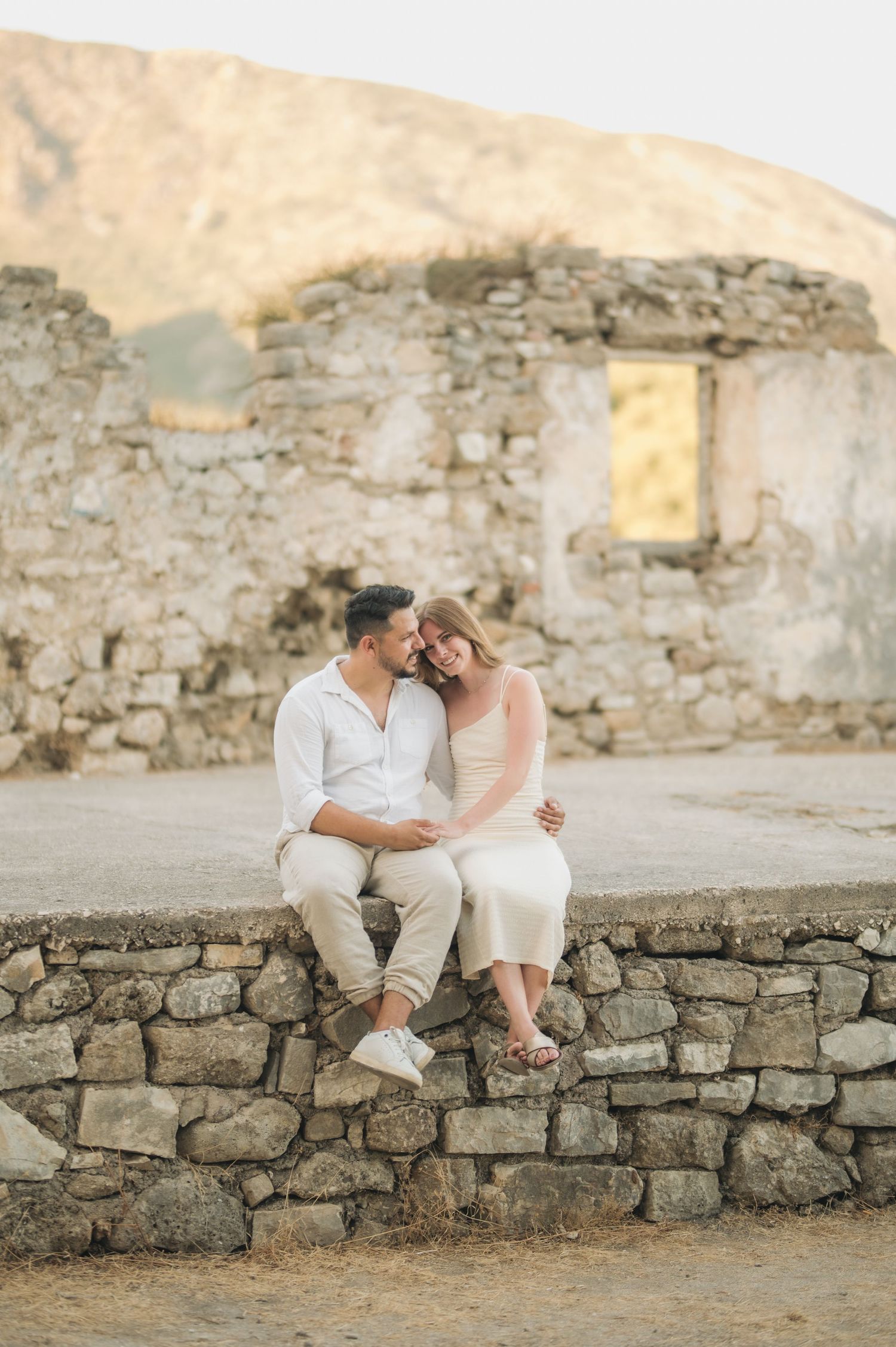 Intimate couple portrait against ancient stone ruins during golden hour.