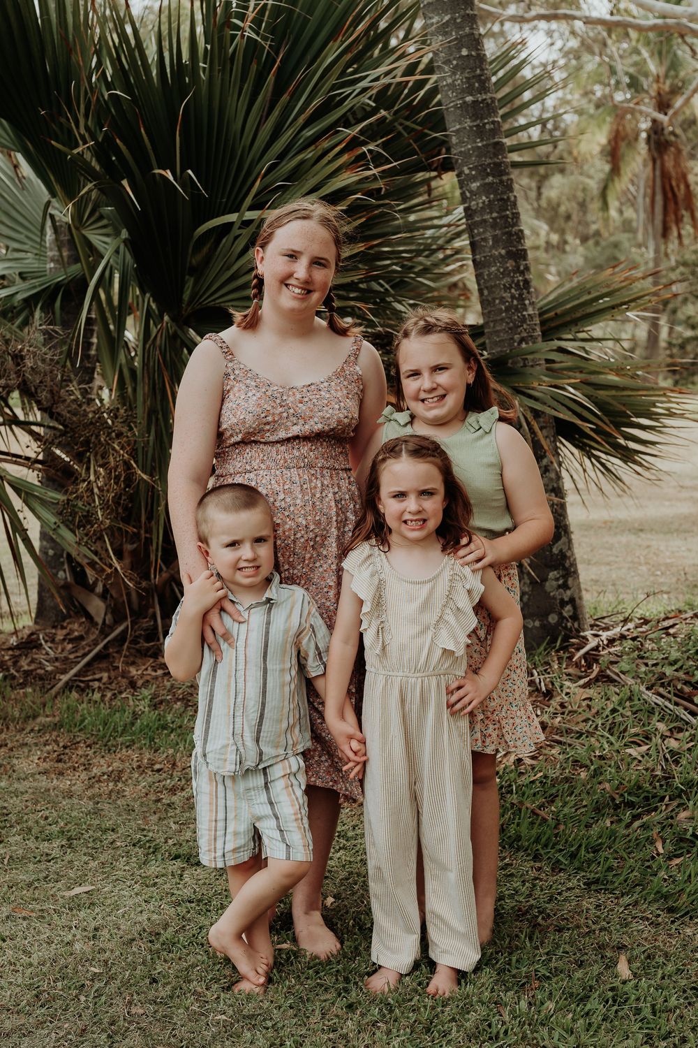 Family group portrait in casual attire against tropical palm background in gladstone.