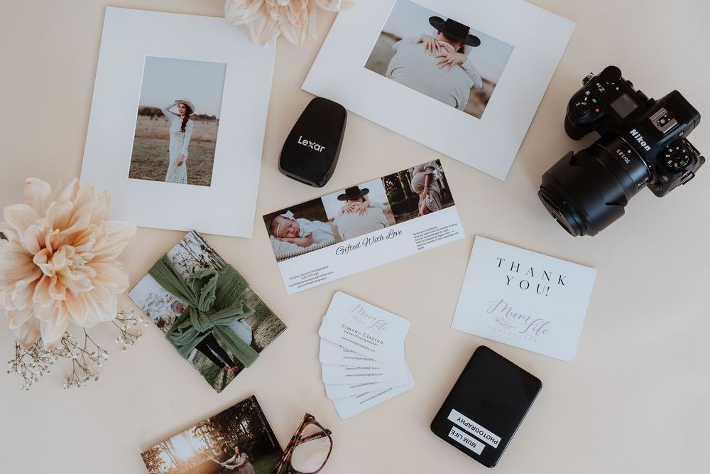 Flatlay of photographs and camera equipment arranged on a beige surface.
