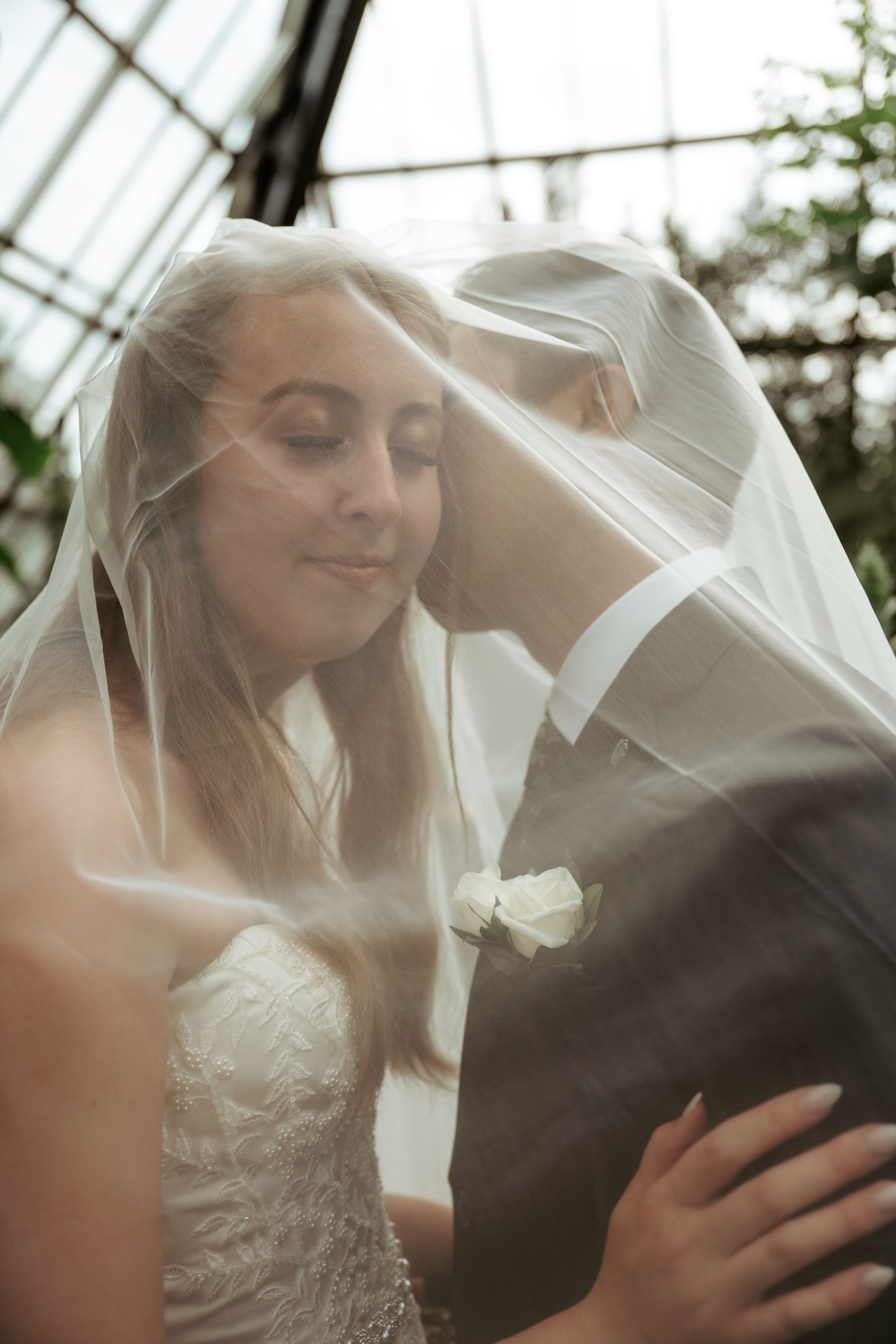 A romantic wedding moment captured as newlyweds share an intimate moment under a delicate white veil.