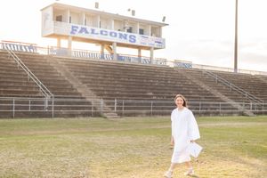 A person in white clothing poses in various positions on empty bleachers at a sports stadium.