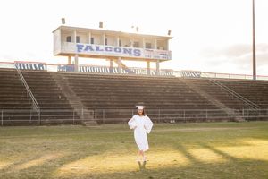 Person in flowing white dress creates artistic silhouette on stadium bleachers at sunset.