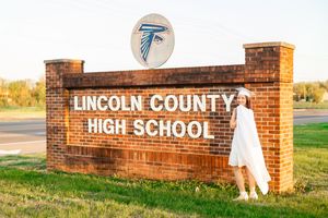 A brick entrance sign for Lincoln County High School with white lettering stands against a sunny rural backdrop.