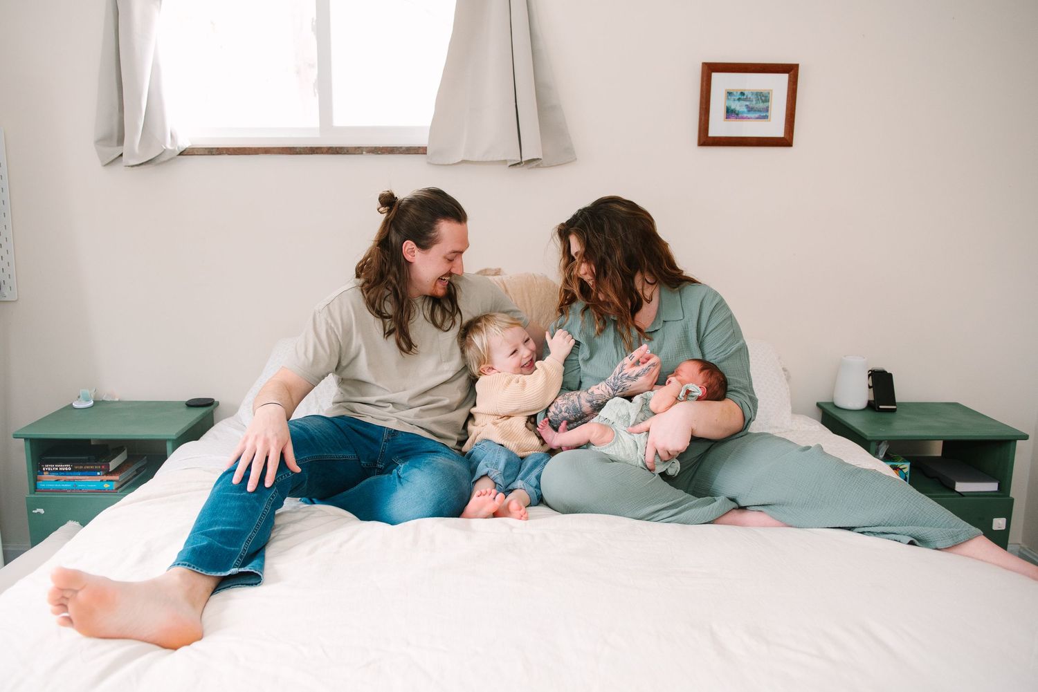 Intimate moment of parents cradling newborn baby on white couch.