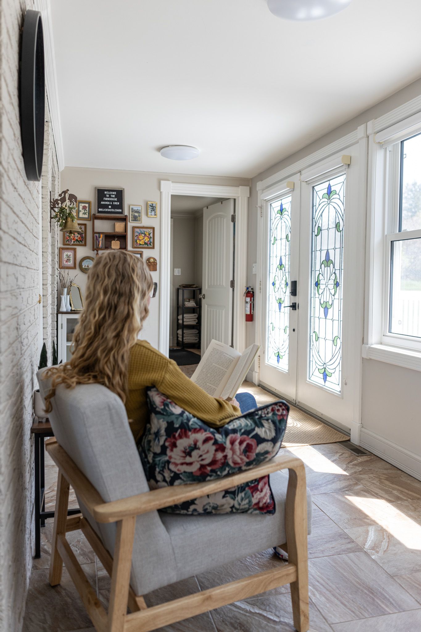 Sunlit entryway featuring a comfortable gray armchair and decorative gallery wall.