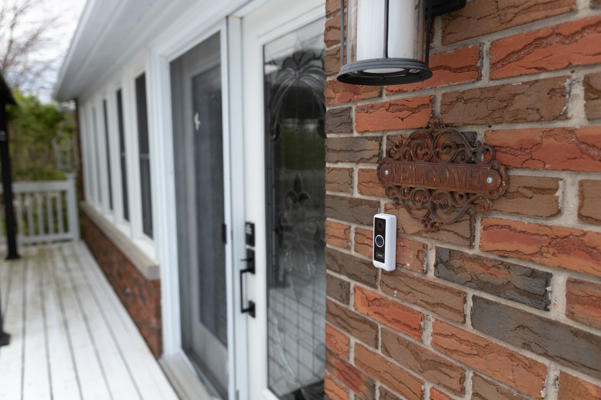 Modern door hardware and brick detail on white-trimmed entrance with wooden deck.
