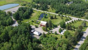 Aerial view of a resort property with cottages and buildings nestled among green trees and ponds.