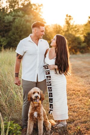 Couple poses with a dog for a pregnancy announcement session in Connecticut