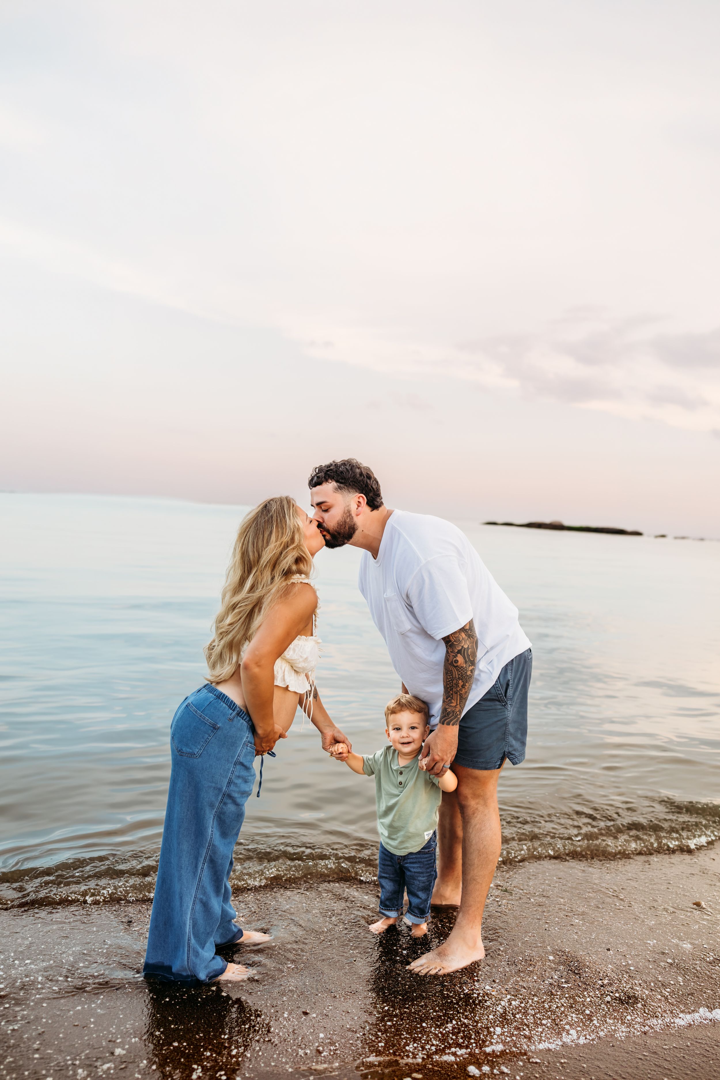 Couple kisses during maternity session at the beach near Guilford, CT during September