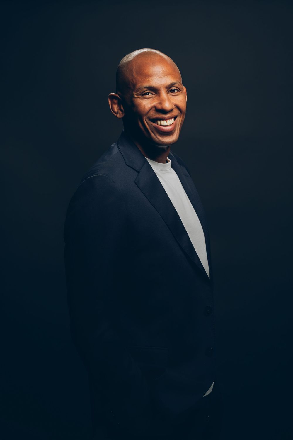 Professional studio portrait series showing warm expressions and poses against a dark background wearing formal attire.