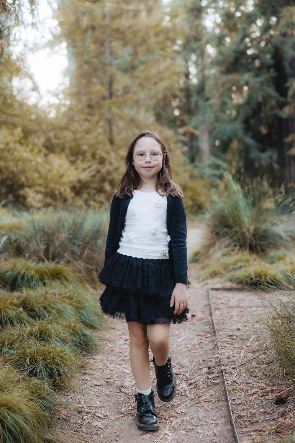 A series of photos showing someone in a black and white dress walking along a dirt path surrounded by autumn foliage.