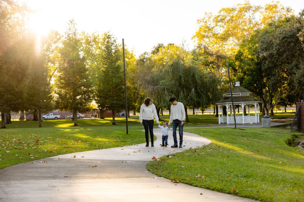 Family walking together on path through sunny autumn park.