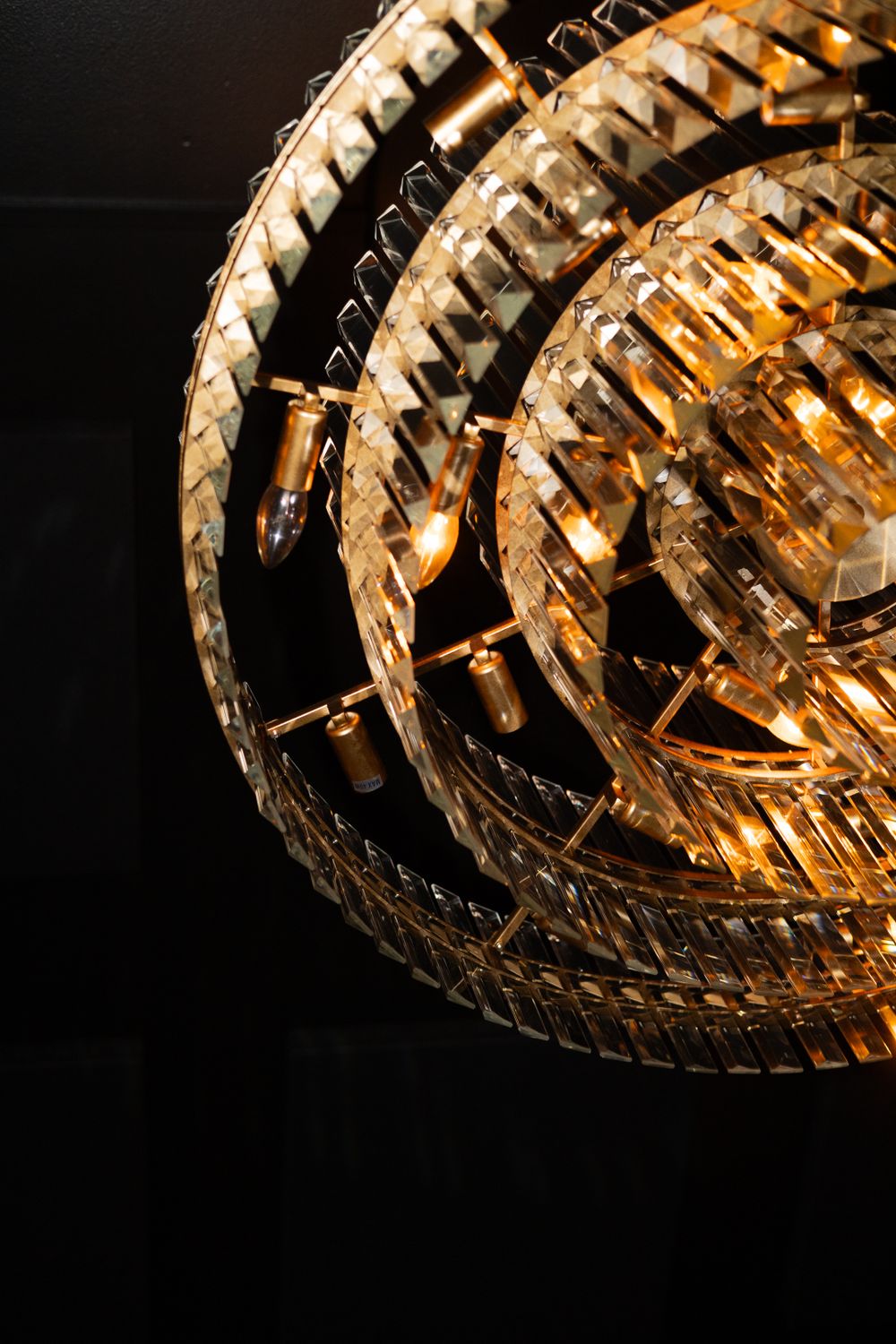 Close-up of an ornate crystal chandelier with golden light reflecting through its intricate design.