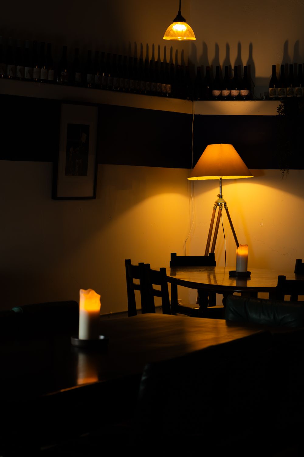 Moody restaurant interior with warm amber lighting and wine bottles silhouetted on shelf.