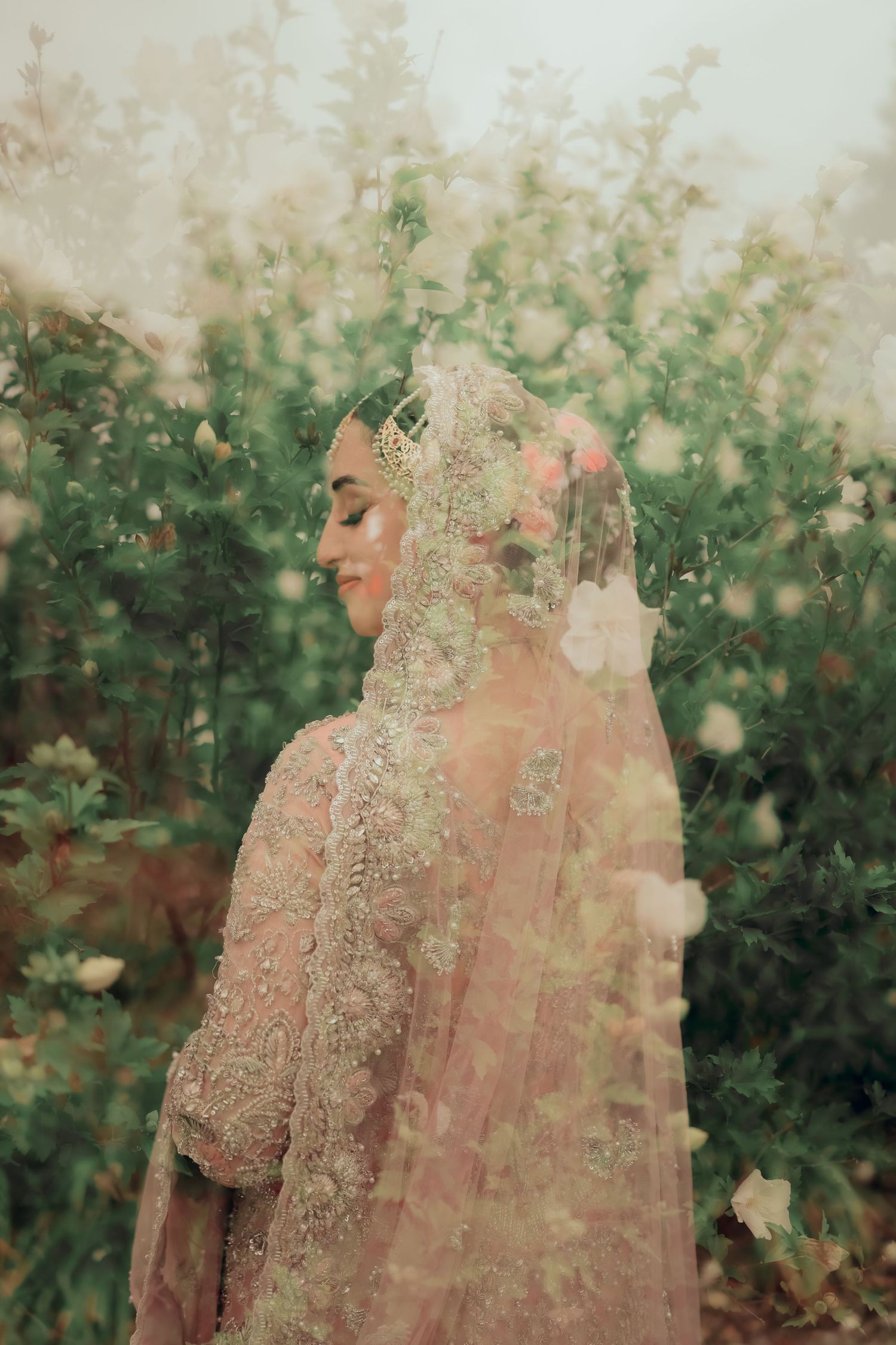 Traditional South Asian wedding couple walking together in a greenhouse among lush plants.