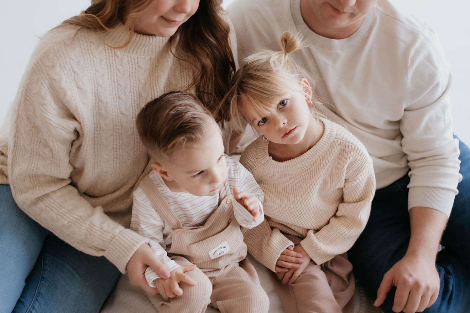 Family wearing neutral colors sits closely together in an intimate portrait. Colorado Springs, Colorado studio photoshoot